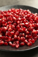 Ripe juicy pomegranate grains on grey table, closeup