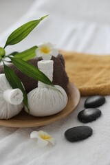 Fototapeta na wymiar Spa stones, flowers and herbal bags on towel indoors, closeup