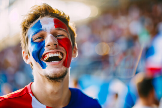 Happy French male supporter with face painted in French flag displaying the country's national colours: blue, white, and red