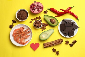 Natural aphrodisiac. Different products and paper heart on yellow background, flat lay