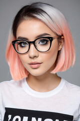 Fototapeta na wymiar Poster of a young attractive woman with short pink and black hair and black glasses for glamorous stylish short haircut idea
