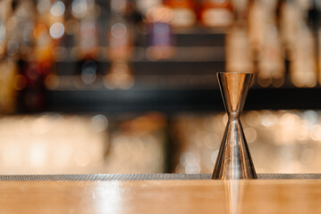 copper jigger on wooden bar table in nightclub, copy space