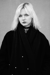 Portrait of a young beautiful blonde girl in a black coat. Black and white photo.