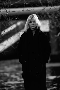 Portrait of a young beautiful blonde girl in a black coat. Black and white photo.