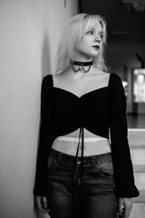 Portrait of a young beautiful blonde girl in a black coat. Black and white photo.