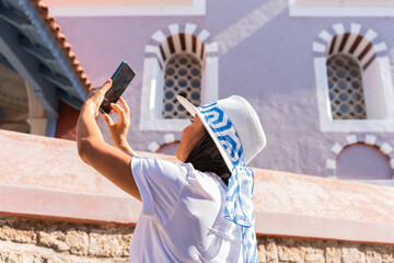 Woman with hat enjoying the historic area of Rhodes town taking a photo on a splendid summer...
