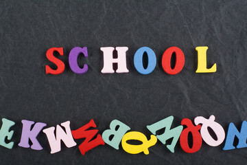 SCHOOL word on black board background composed from colorful abc alphabet block wooden letters, copy space for ad text. Learning english concept.