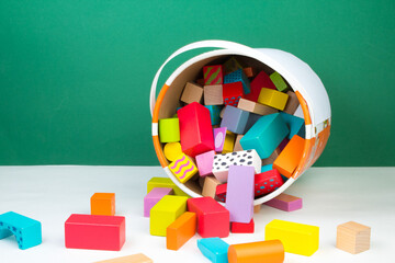 Children's toy, wooden constructor, poured out of a bucket on a green background. Kids toys. - obrazy, fototapety, plakaty