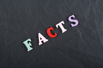 FACTS word on black board background composed from colorful abc alphabet block wooden letters, copy space for ad text. Learning english concept.