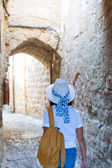 Woman with hat entering the historical and monumental area of the Greek city of Rhodes on a...