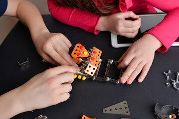 Children assemble robot, showcasing engineering skills. Top-down view of table. Concept of...