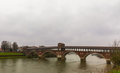 Fototapeta premium Ponte Coperto (Covered bridge) over river Ticino in Pavia, Italy on a rainy day