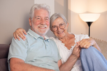 Happy bonding loving senior couple sitting on sofa, looking at camera, recollecting good memories or planning common future, enjoying peaceful moment together at home.