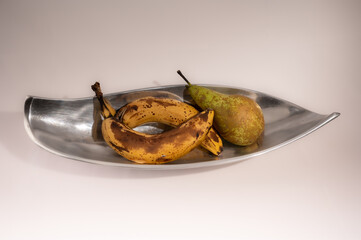 Birne und Bananen in Obstschale aus Metall