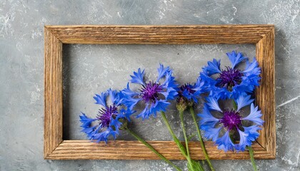 five blue nice cornflowers in a wooden frame over grey simple flowers