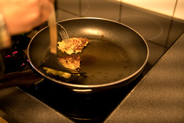 Potato pancakes are turned with the help of a fork and spatula
