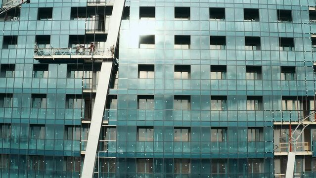 Facade of moderm multi-storey glass building under construction with crane on the top. Construction site. Architecture abstract background. Building skyscraper house, industrial development