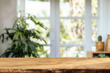 Wooden table top with blurred green plants and garden view through the window. High quality photo