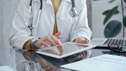 Doctor woman using tablet on the glass desk in medical office. Medicine and health care