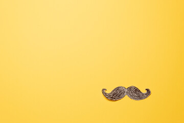 Paper mustache isolated with curly tips at the bottom corner on yellow background