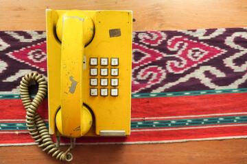 Yellow old fashioned landline telephone that uses the number buttons system to call. Ancient analog...