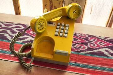 Yellow old fashioned landline telephone that uses the number buttons system to call. Ancient analog...