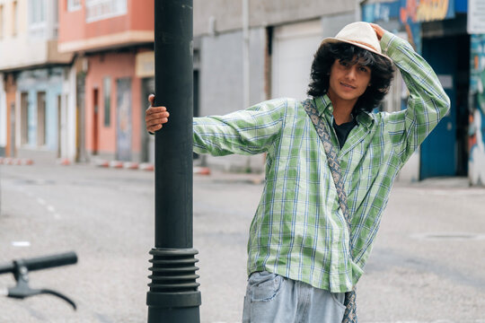funny young man leaning on street lamp