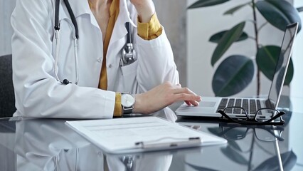 Doctor reviewing medical records on laptop. Close-up of a healthcare professional analyzing patient information on a computer