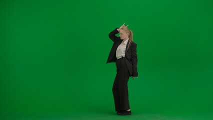 Woman in black business suit dancing cheerfully on green screen with chromakey.