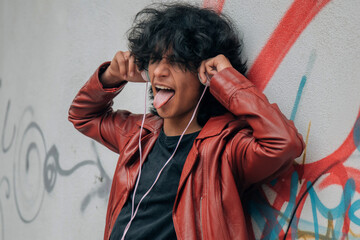 young urban man with headphones and rebellious expression on the street