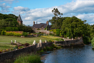 Calm river flows by a grand country mansion surrounded by lush, blooming garden