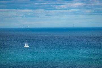 Sailing ship with unfurled white sails travels along the deep blue North Sea