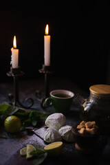 Homemade marshmallow with mint and lime, on the black table, where there are two vintage candles that burn