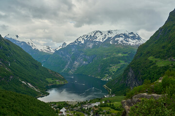 Fototapeta na wymiar Beautiful Geiranger Fjord is a well known and popular travel destination for cruise ships and offers spectacular views to the norwegian landscape with deep gorges and snow covered mountain ranges.