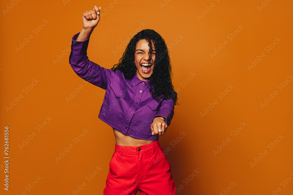 Wall mural Vibrant woman dancing with joy on colourful background