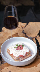 Belgian waffles with strawberry confit and cream sauce and glass on wooden table in cafe