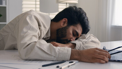 Lazy weary sleepy male manager tired exhausted Arabian Indian businessman employee working computer...