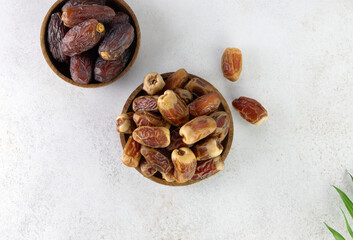 Variety of dried dates fruits in a wooden bowl on a white background.