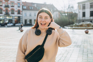 Fascinating exultant charismatic young woman doing phone gesture like says call me back isolated on...