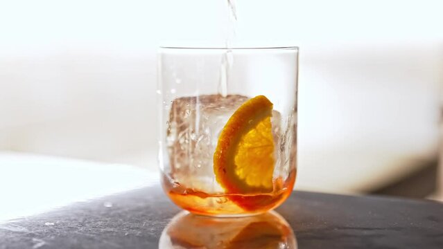 Pouring classic Negroni cocktail with ice.
