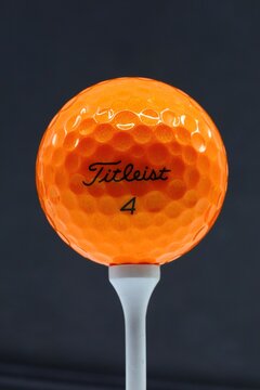 Titleist orange golf ball on a course tee. Orlando, Florida, USA - March 12