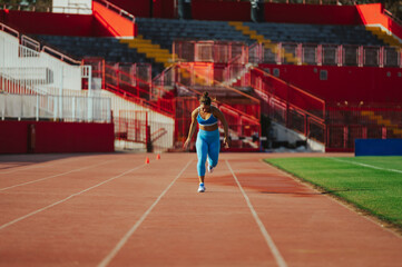 Portrait of a female runner in a blue active wear racing at the stadium