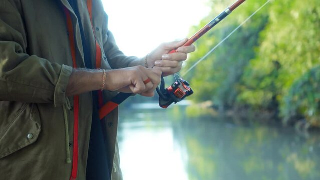 Fishing in nature with a man in a tourist robe. Men's hands hold a fishing rod.