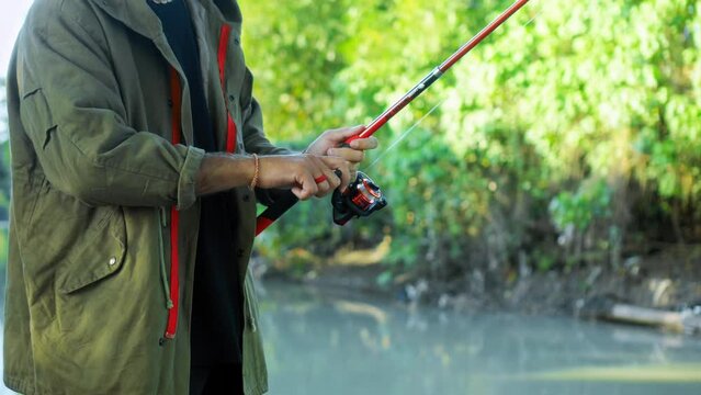 Fishing in nature with a man in a tourist robe. Men's hands hold a fishing rod.