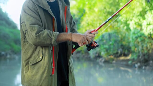 Fishing in nature with a man in a tourist robe. Men's hands hold a fishing rod.