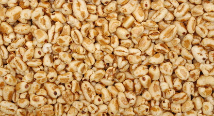 Puffed wheat cereal flakes with honey background and texture, top view