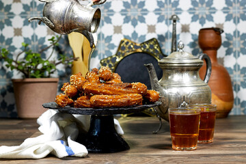 woman pouring a honey sirup on algeria oriental Balah el sham dessert fritters named zlabiat al...