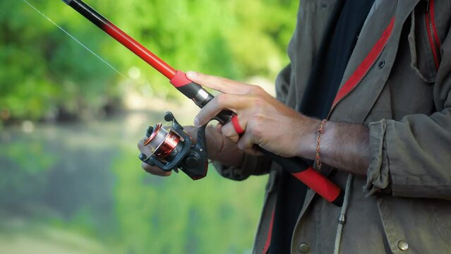 Fishing in nature with a man in a tourist robe. Men's hands hold a fishing rod.