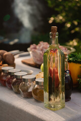 Fresh vegetables and raw meat with spices and oil on the table in nature in the warm sunny light. ingredients ready for cooking on grill outdoors on family picnic 