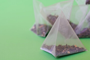 Triangular translucent pyramid tea bags with tea on a green background. The drink of long-livers. Photo. Macro. Selective focus